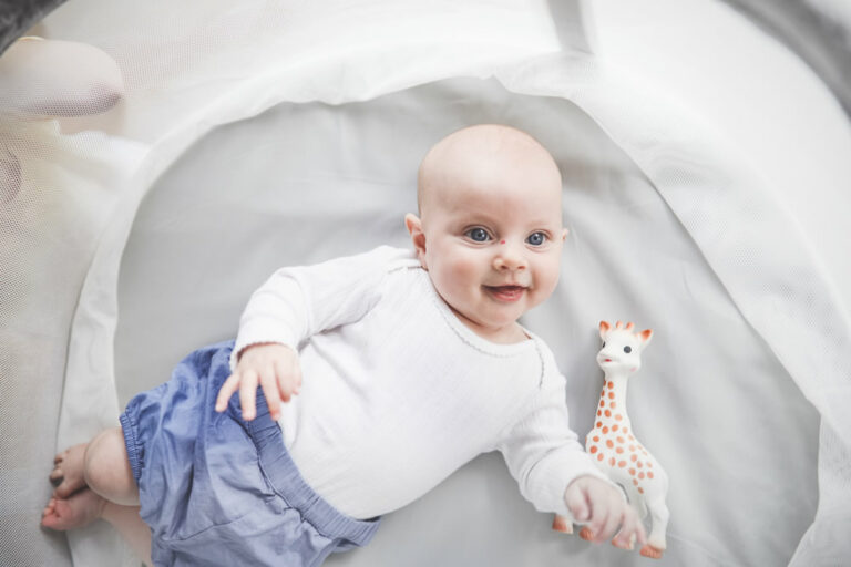 Baby spielt mit Giraffe in der Babywiege
