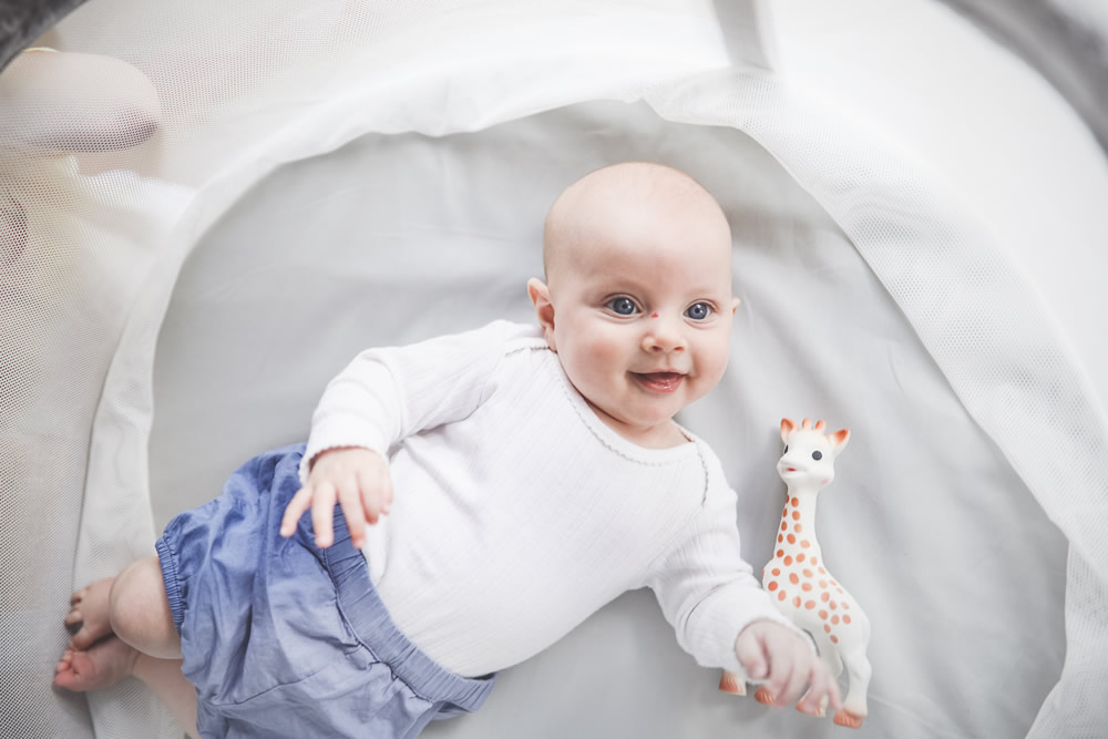 Baby spielt mit Giraffe in der Babywiege